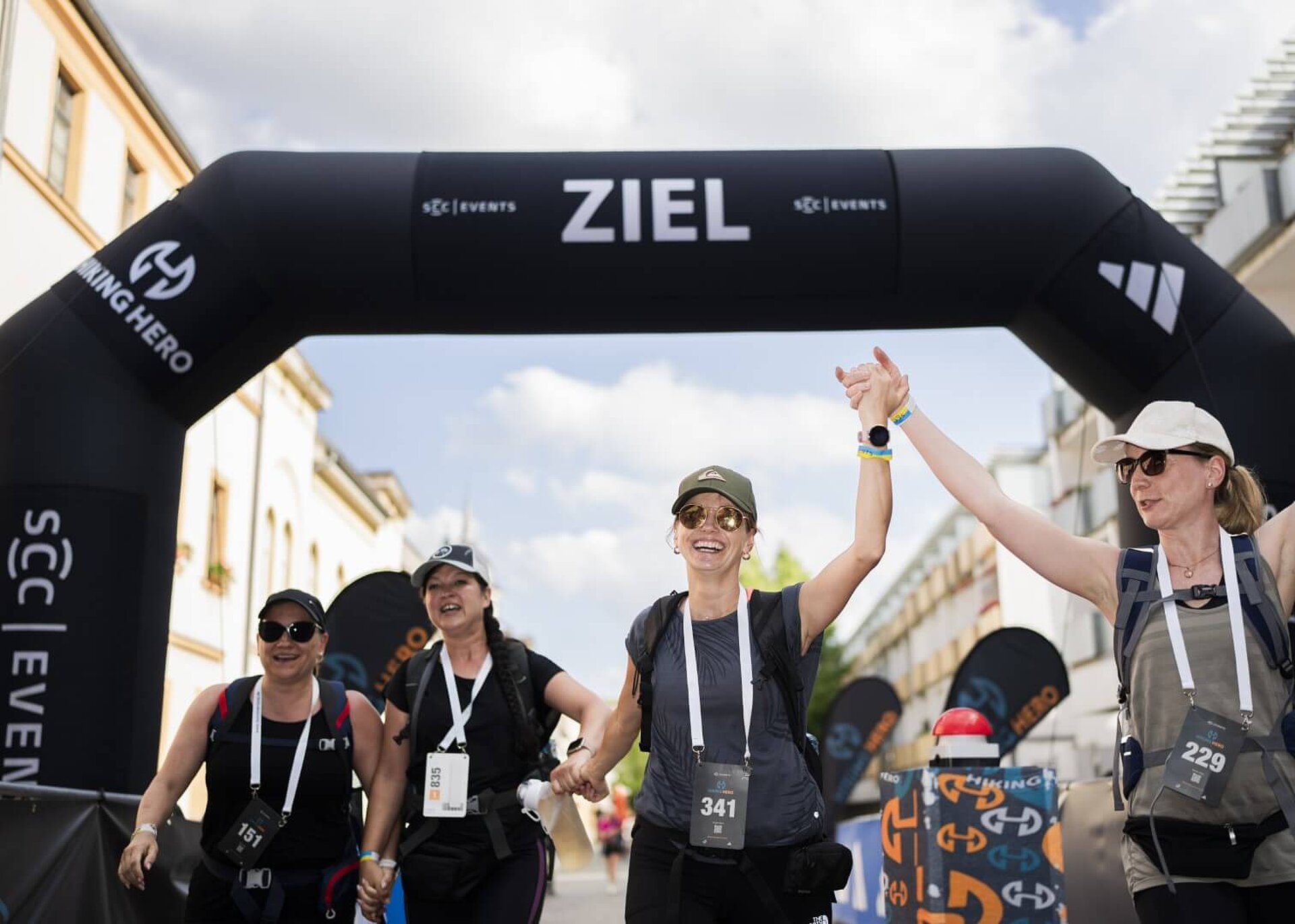 Vier Teilnehmerinnen durchqueren mit breitem Lächeln Hand in Hand das Zieltor.