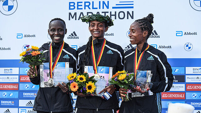 Die Frauen bei der Siegerehrung. In der Mitte steht Tigist Assefa mit einem Lorbeerkranz auf dem Kopf, links neben ihr steht Rosemary Wanjiru, rechts steht Tigist Abayechew.