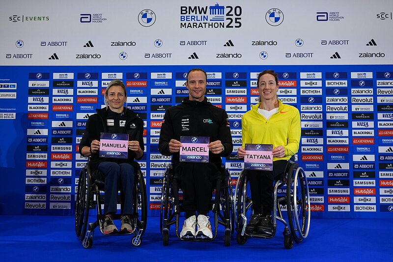 From left to right: Manuela Schär, Marcel Hug, and Tatyana McFadden hold up their race numbers for the camera.