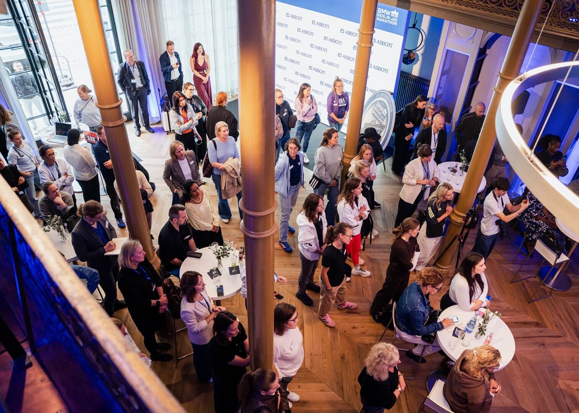 From above: About 40 people in the audience watching the panel discussion in a room with tall columns.