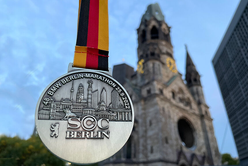 Die Medaille des Berlin-Marathon mit Sehenswürdigkeiten und der Gedächtnis-Kirche im Hintergrund.