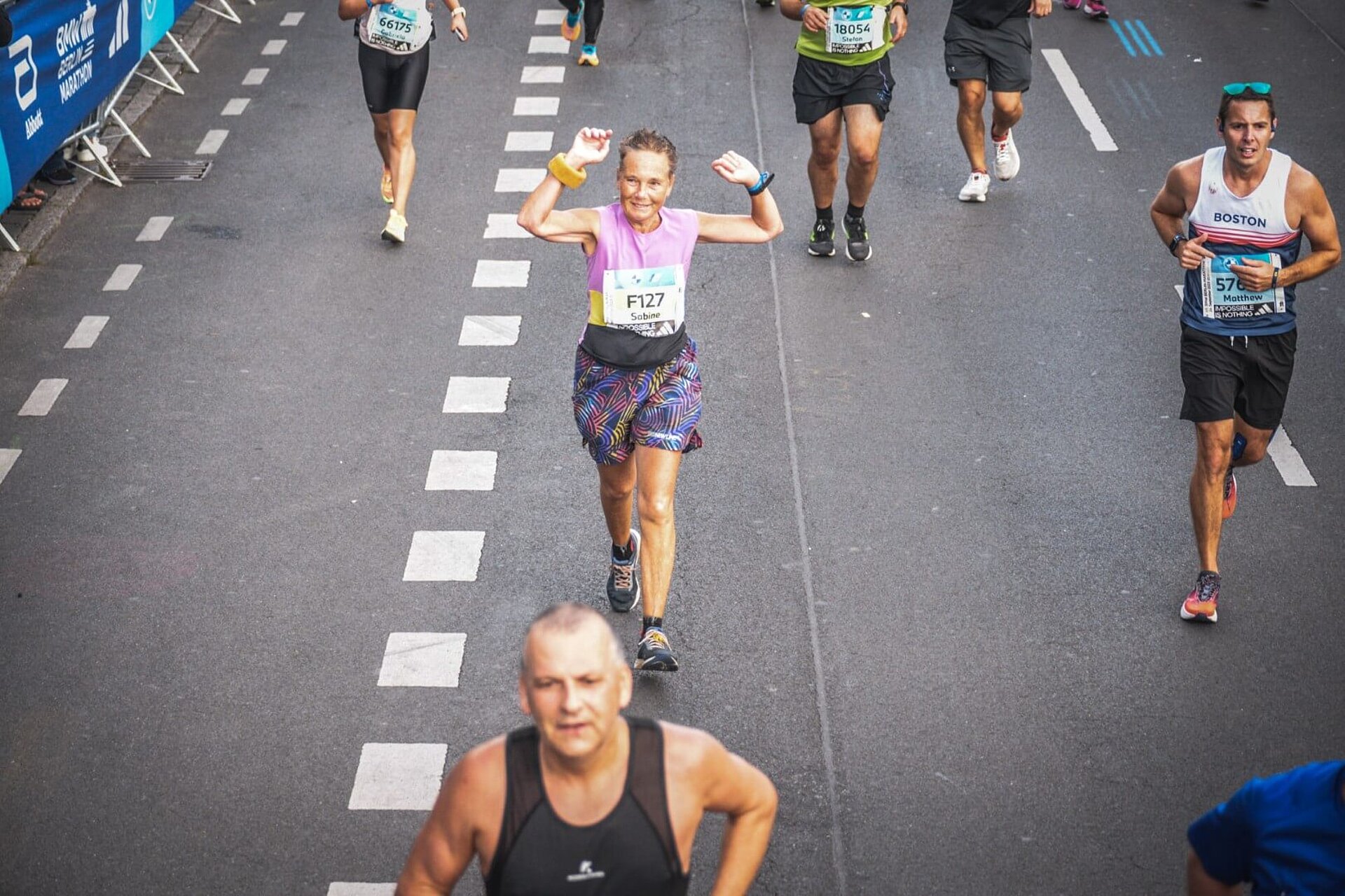 Sabine jubelt mit erhobenen Armen auf der Strecke des BERLIN-MARATHON.