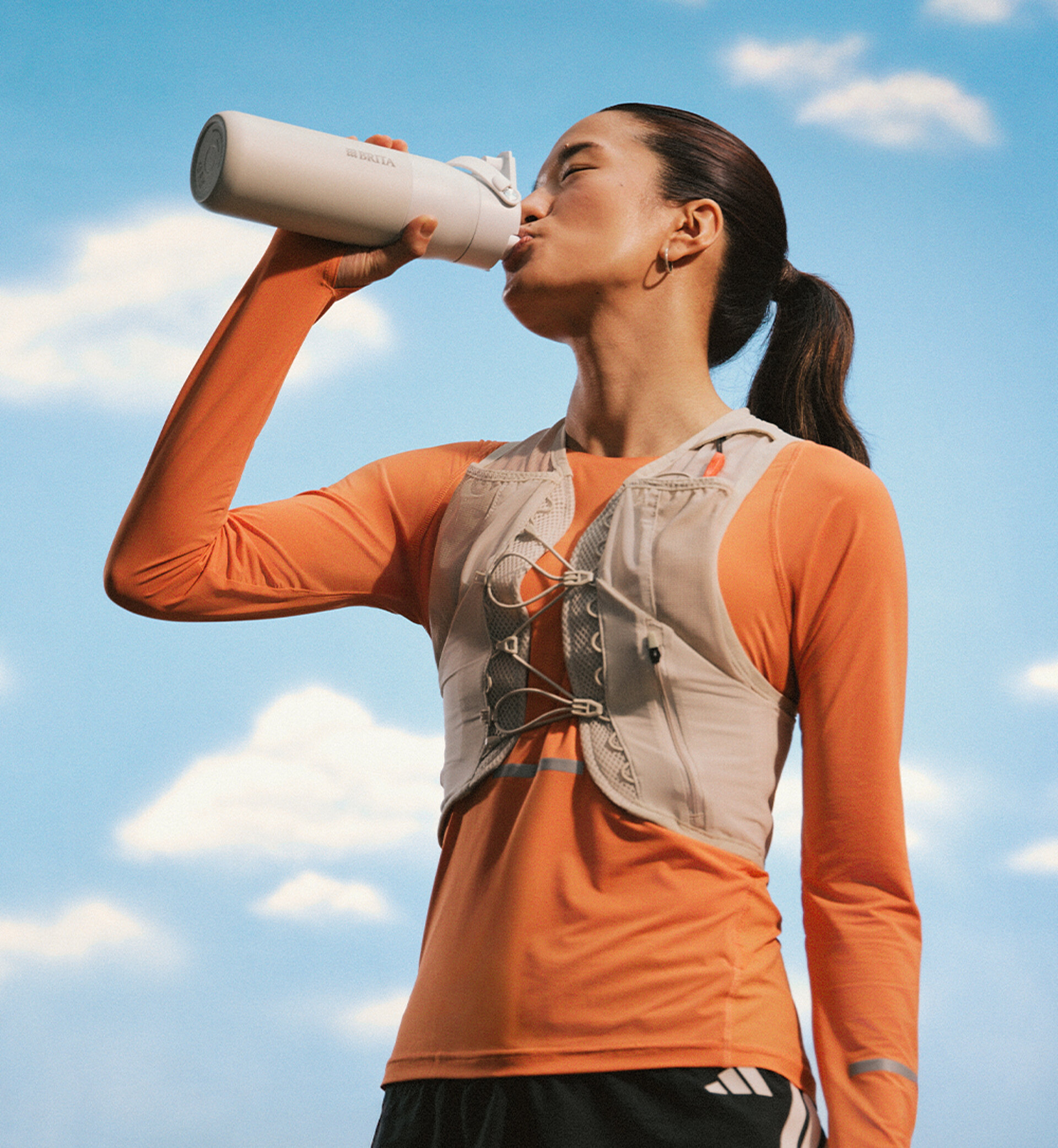 Female athlete enjoys drinking from her waterbottle.