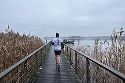 Berlin New Year's Eve run: Man trains in the cold and runs along a footbridge towards the lake © SCC Events